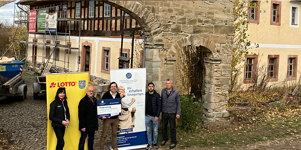 Gruppenbild der Anwesenden bei der Förermittelübergabe vor dem historischen Torbogen